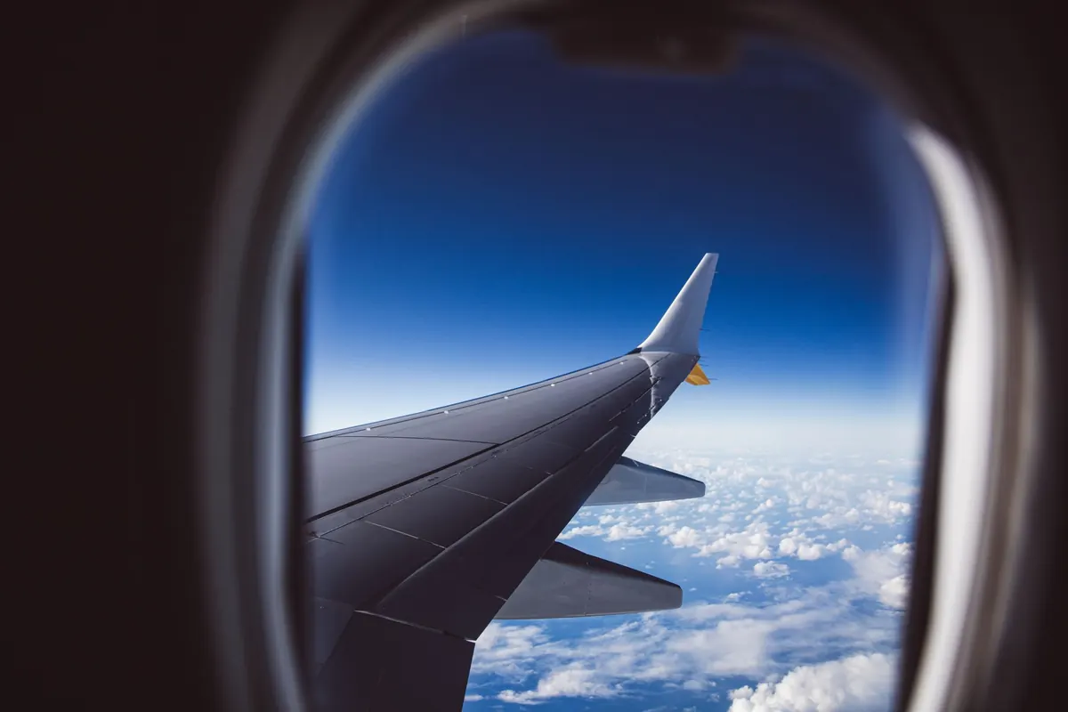 飛行機の窓から見える主翼と雲海